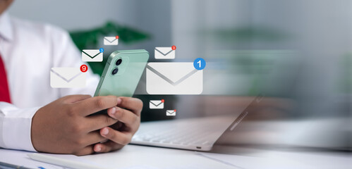 Email, contact, online communication, messaging, and business correspondence in a modern office. Close-up of businessman holding smartphone with digital email icons and notifications.