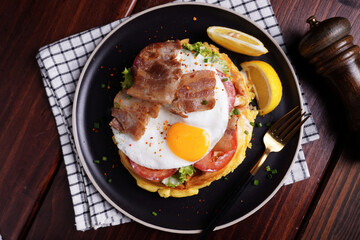 Fried Egg and Pork Waffles Food in a black plate on a wooden table