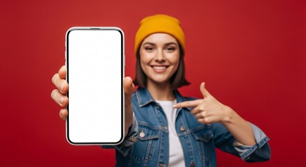 Smiling young woman pointing to blank smartphone screen – mockup space for app, website, or marketing design