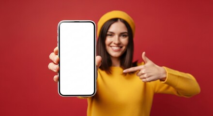 Smiling young woman pointing to blank smartphone screen – mockup space for app, website, or marketing design