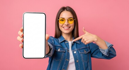 Smiling young woman pointing to blank smartphone screen – mockup space for app, website, or marketing design