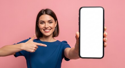 Smiling young woman pointing to blank smartphone screen – mockup space for app, website, or marketing design