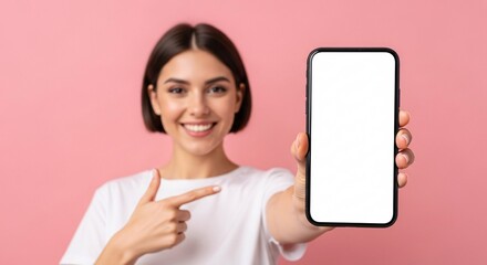 Smiling young woman pointing to blank smartphone screen – mockup space for app, website, or marketing design