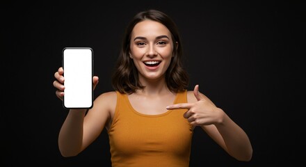Smiling young woman pointing to blank smartphone screen – mockup space for app, website, or marketing design