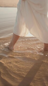 A woman in a flowing white dress walks through shallow, clear water on a sunny beach. The video evokes feelings of peace, tranquility, and the beauty of nature.