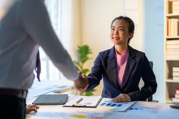Asian businesswoman shaking hands with businessman concluding a successful deal