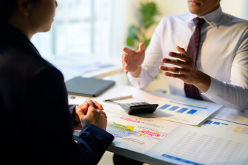 Business partners discussing business plan using charts and calculator