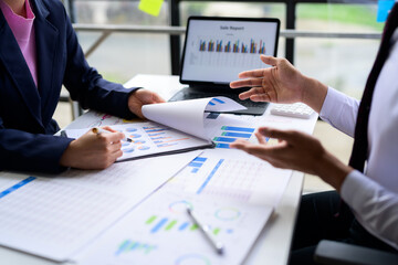 Business people analyzing financial charts and discussing sales reports in the office