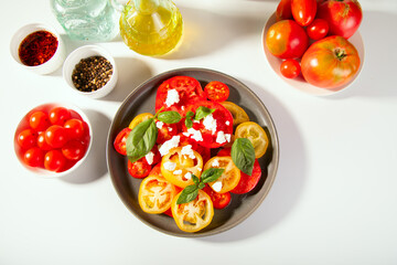 Sliced fresh tomato salad with basil leaves sprinkled with feta cheese
