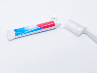 A tube of toothpaste and a toothbrush sit on a clean white background, representing oral hygiene and dental care. Perfect for health and wellness concepts.