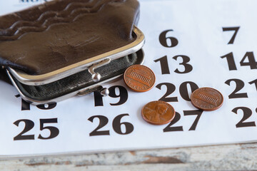 One cent coins falling out of old wallet onto calendar with month dates, social benefits and...
