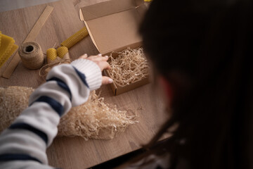 Candle making at home. SME and hobbies. Woman makes beeswax candle and packing in gift box for...