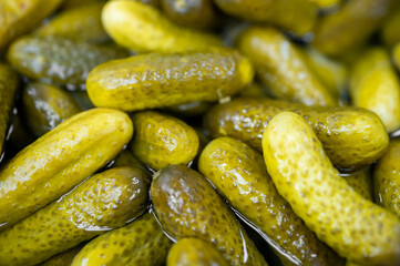 Close-up of fresh green pickles submerged in brine, highlighting their crisp texture and appetizing...