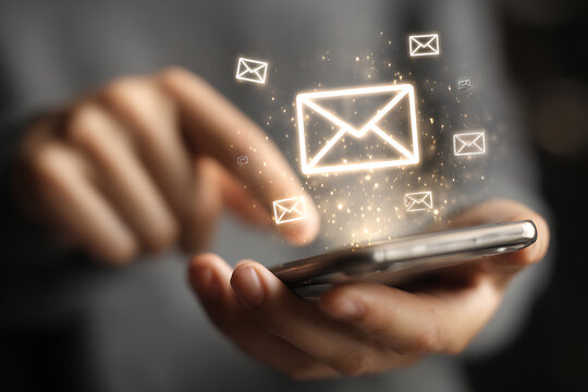 Person using smartphone to send glowing email notifications with sparkling light effects, representing digital communication and connectivity.