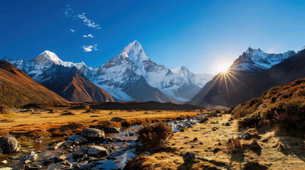 Majestic snow capped mountain range under clear blue sky, with sunlight illuminating peaks and serene stream flowing through valley, creating breathtaking landscape