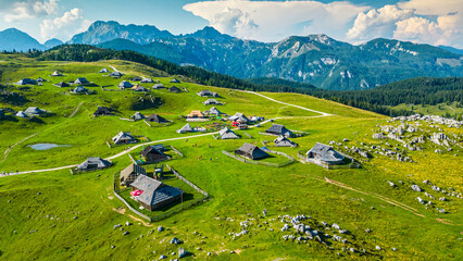 Aerial panoramic view of Velika Planina in Slovenia featuring vast green alpine pastures dotted...