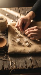 Handcrafting with natural fibers: hands arranging fluffy cotton on burlap fabric in warm light