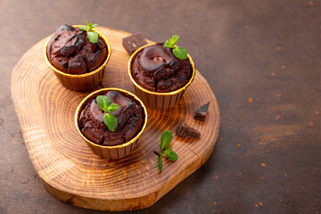 Chocolate brownie muffins with mint on dark background, copy space for text