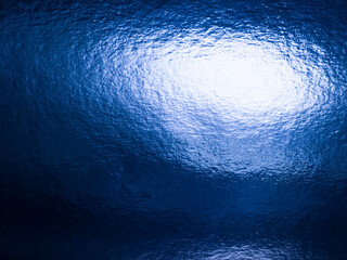 Abstract blue textured background with shimmering light reflection