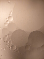 Abstract closeup of oil bubbles in water with soft beige lighting