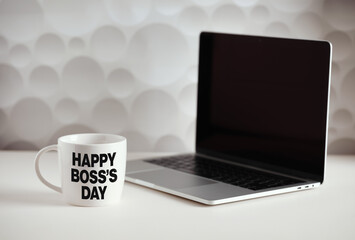 Celebrating Boss's Day with a personalized mug and laptop on a white desk