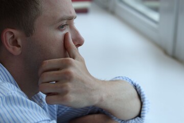 Sad man crying alone indoors, closeup. Depression and anxiety