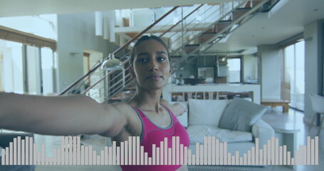 Stretching woman wearing pink sports top extending arms in open plan living room, with white sofa