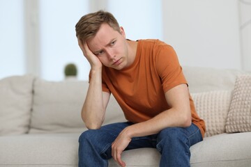 Sad thoughtful man on sofa at home