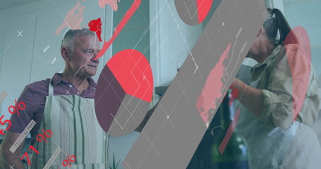 Cooking senior man and mature woman chopping vegetables wearing aprons in kitchen, with data charts