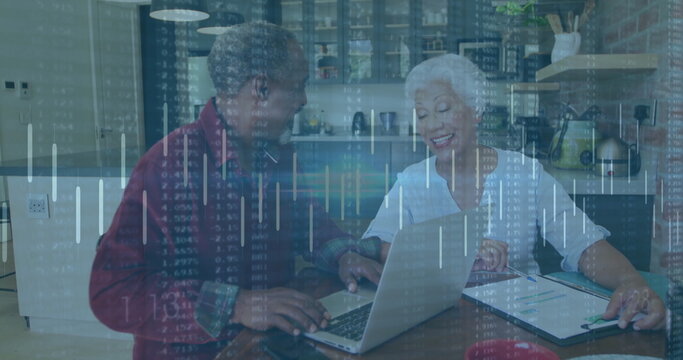 Senior couple reviewing financial data on silver laptop in modern kitchen, with clipboard and pen - Powered by Adobe