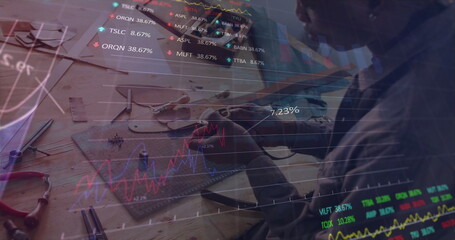 Craftsman in sweatshirt assembling wood piece on workbench with tools and stock graphs, copy space