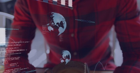Programmer in red plaid shirt analyzing holographic overlays in office, with laptop and coffee mug