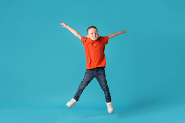 Cute little boy jumping on light blue background