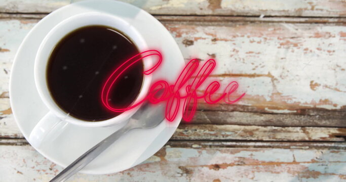 Fototapeta Showing white porcelain coffee cup resting on cafe countertop, with neon Coffee script, copy space