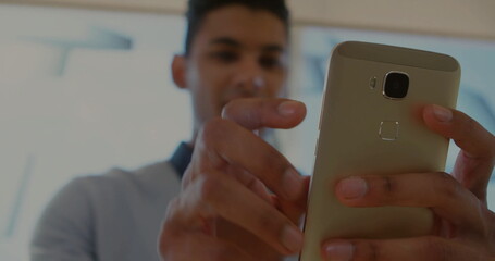 Holding gold smartphone with both hands, adult man interacting with touchscreen in showroom windows