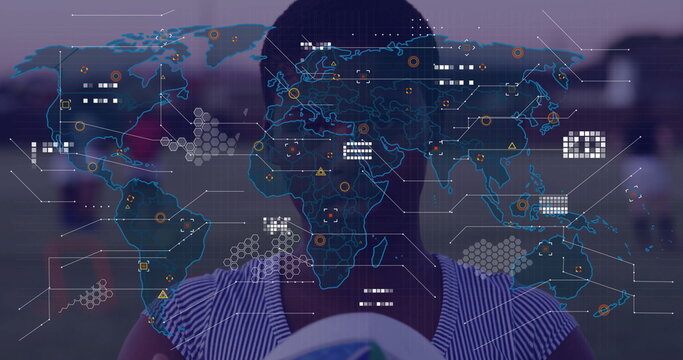 Fototapeta Holding soccer ball soccer player wearing jersey standing on field, with digital world map overlay