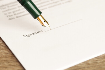 Signing notary document with fountain pen at wooden table, selective focus