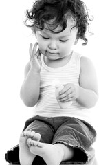 Curly haired toddler applying lotion or cream