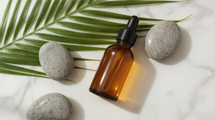 Minimalist composition of an amber glass dropper bottle surrounded by gray spa stones and a tropical palm leaf on a white marble background, ideal for beauty, skincare, and wellness themes.