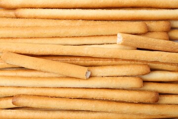 Delicious grissini sticks as background, top view