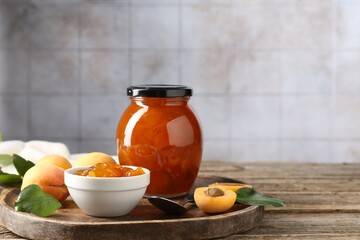 Tasty apricot jam and fresh fruits on wooden table, closeup. Space for text
