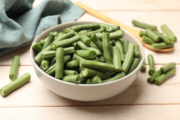 Pieces of fresh pea pods in bowl on light wooden table, closeup