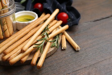 Delicious grissini sticks and rosemary on wooden table, closeup