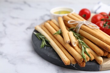 Delicious grissini sticks and rosemary on light grey marble table, closeup