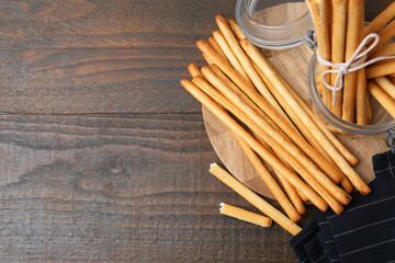 Delicious grissini sticks on wooden table, flat lay. Space for text
