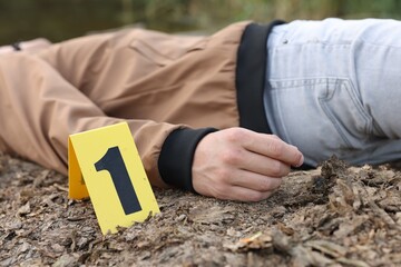 Forensic expertise. Crime scene with dead man's body and marker outdoors, closeup