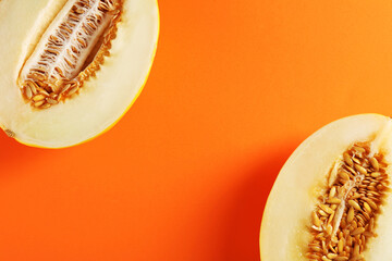 Halves of ripe melon on orange background, flat lay. Space for text