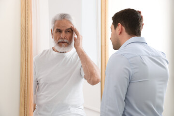Man seeing himself as elder in mirror. Conceptual collage about past and future, flow of time, age