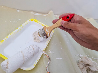Close-up view of hands carefully applying protective yellow tape around white electrical outlet...