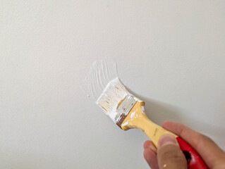 Professional painting tools including red-handled brush and yellow tape positioned for interior wall renovation work